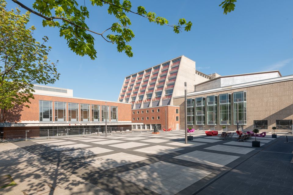 Außenhof mit modernisiertem Gebäudekomplex und markantem Hochbau unter blauem Himmel