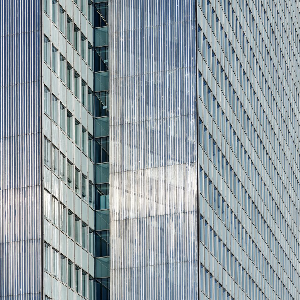 Detailansicht einer strukturierten Metallfassade eines Hochhauses mit vertikal geführten Profilen und integrierten Fensterbändern.