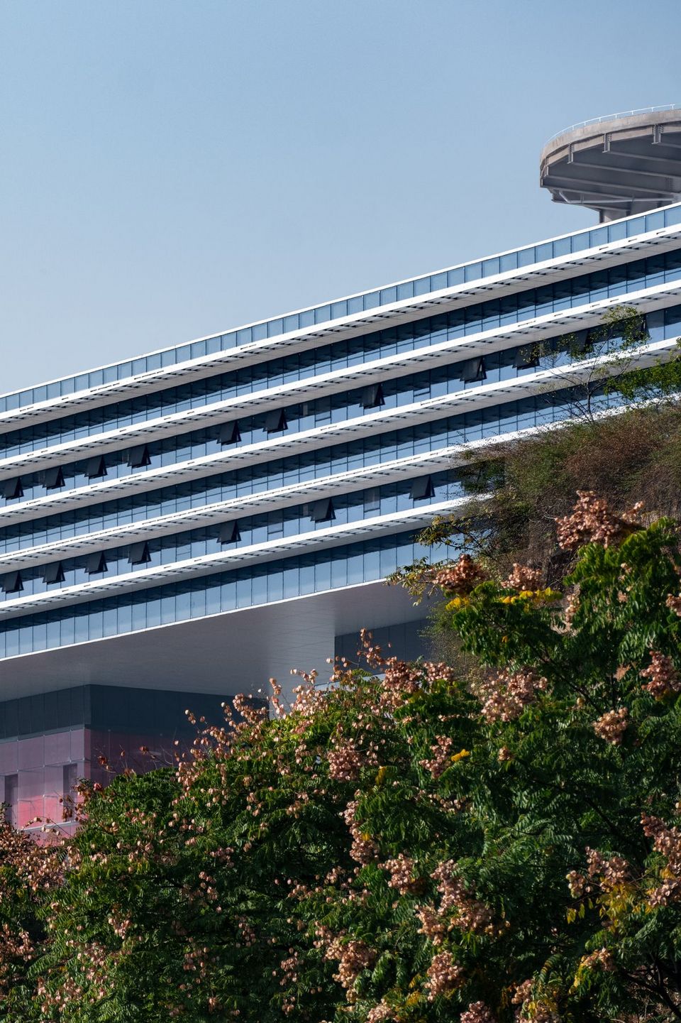 Low‑angle exterior view of the broadcasting building with a prominent cantilevered roof and continuous glazing.