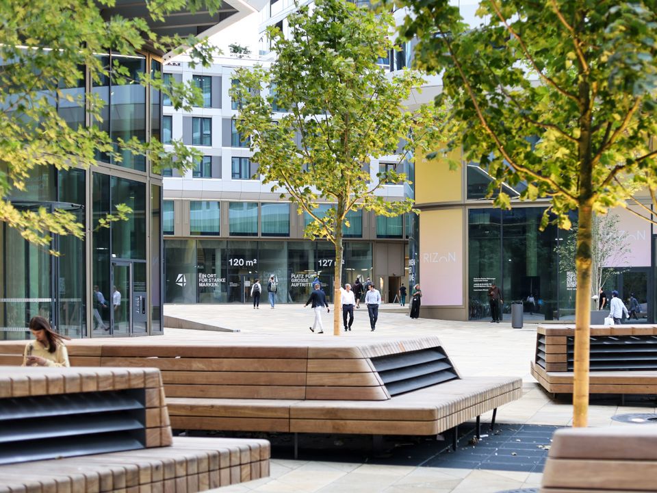 Außenansicht eines Hochhauses mit verglasten Fassadenflächen, vertikal betonten Strukturlinien und angrenzenden Stadträumen.