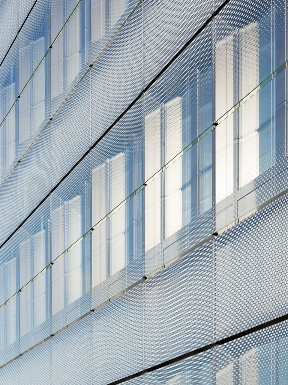 Nahaufnahme einer strukturierten Glasfassade mit vertikalen Fensterbändern und feiner Punktmusterung.