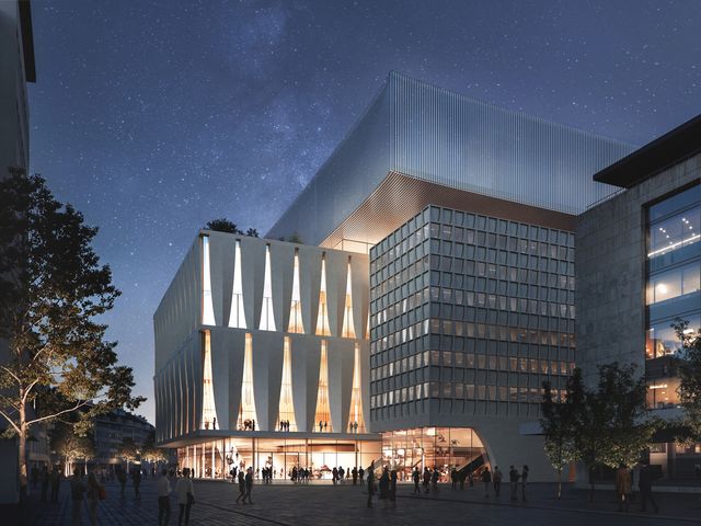 Außenaufnahme eines Kulturgebäudes im nächtlichen Stadtkontext mit vertikaler Fassadenstruktur, transparenten Sockelbereichen und belebtem öffentlichen Raum.