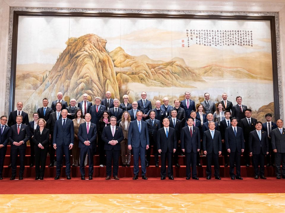 Gruppenaufnahme einer großen Delegation in einem repräsentativen Saal vor einem Wandgemälde mit Landschaftsmotiv, aufgenommen während eines offiziellen Termins.