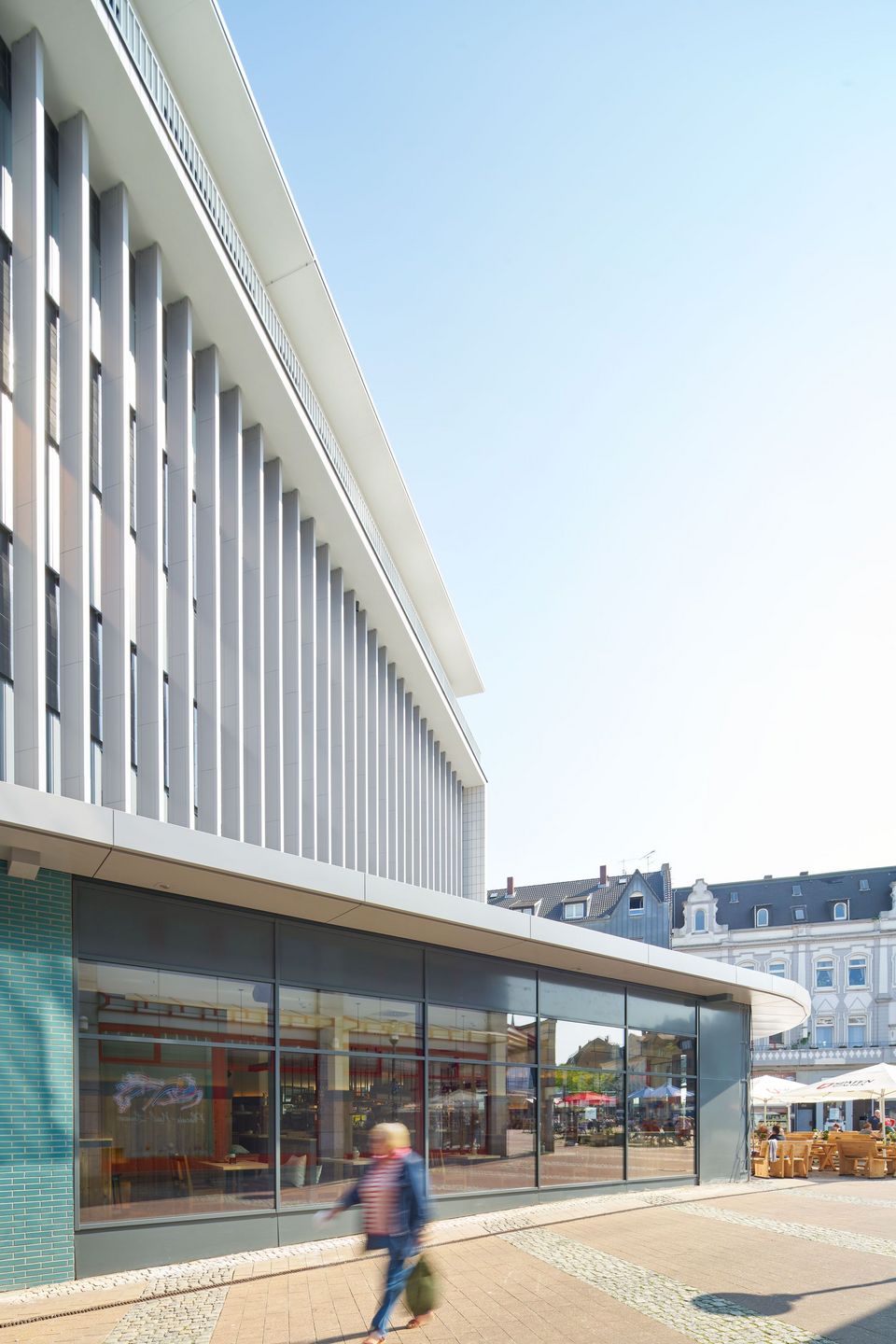 Detailansicht der Fassade eines modernen Gebäudes mit vertikalen Lamellen, Blick auf angrenzende historische Bebauung