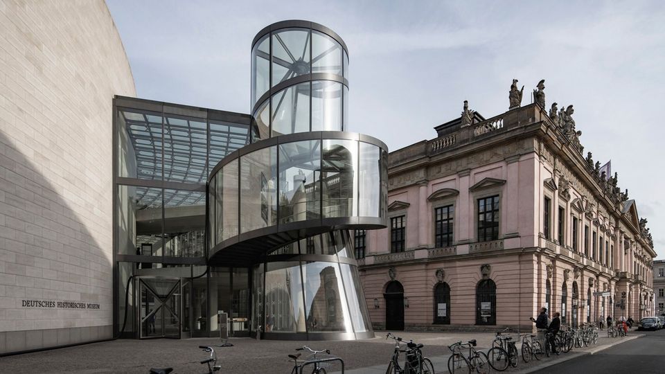 Außenansicht eines Museumsbaus mit moderner Glasstruktur im Dialog mit historischer Architektur.