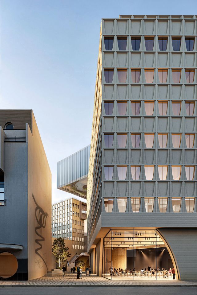 Außenaufnahme eines modernen Kultur- und Bürogebäudes mit skulpturaler Fassadenstruktur, großem Eingangsbereich und kompakter Stadtraumsequenz zwischen zwei Baukörpern.