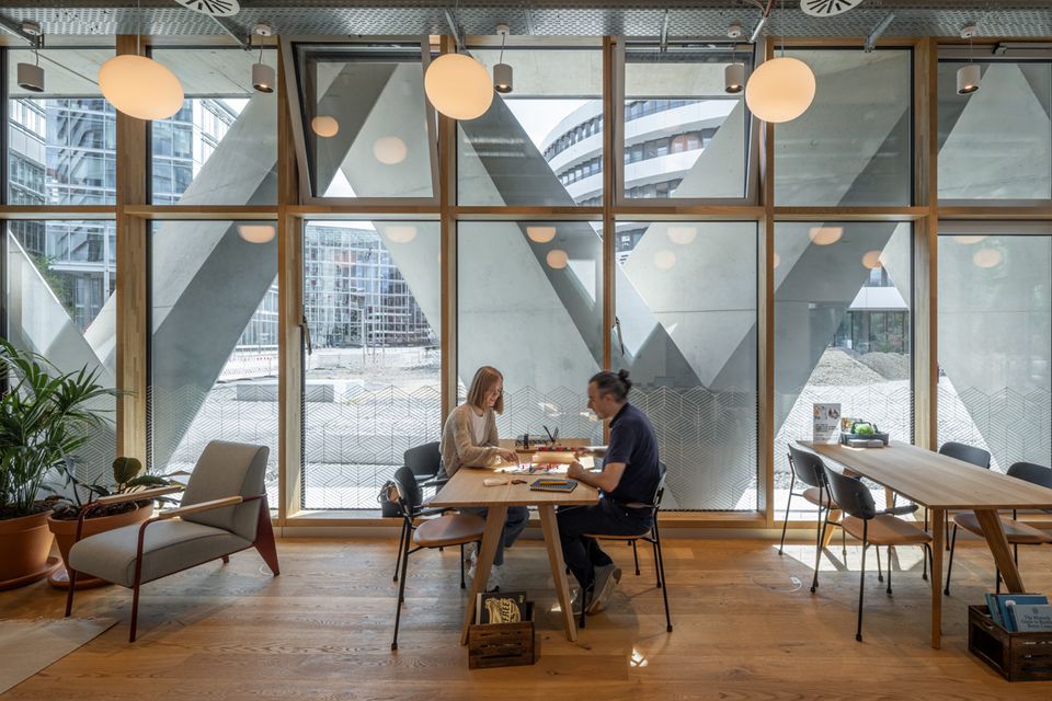 Interior with large glass fronts and view of the striking triangular structure of the façade, modern working environment with wooden flooring