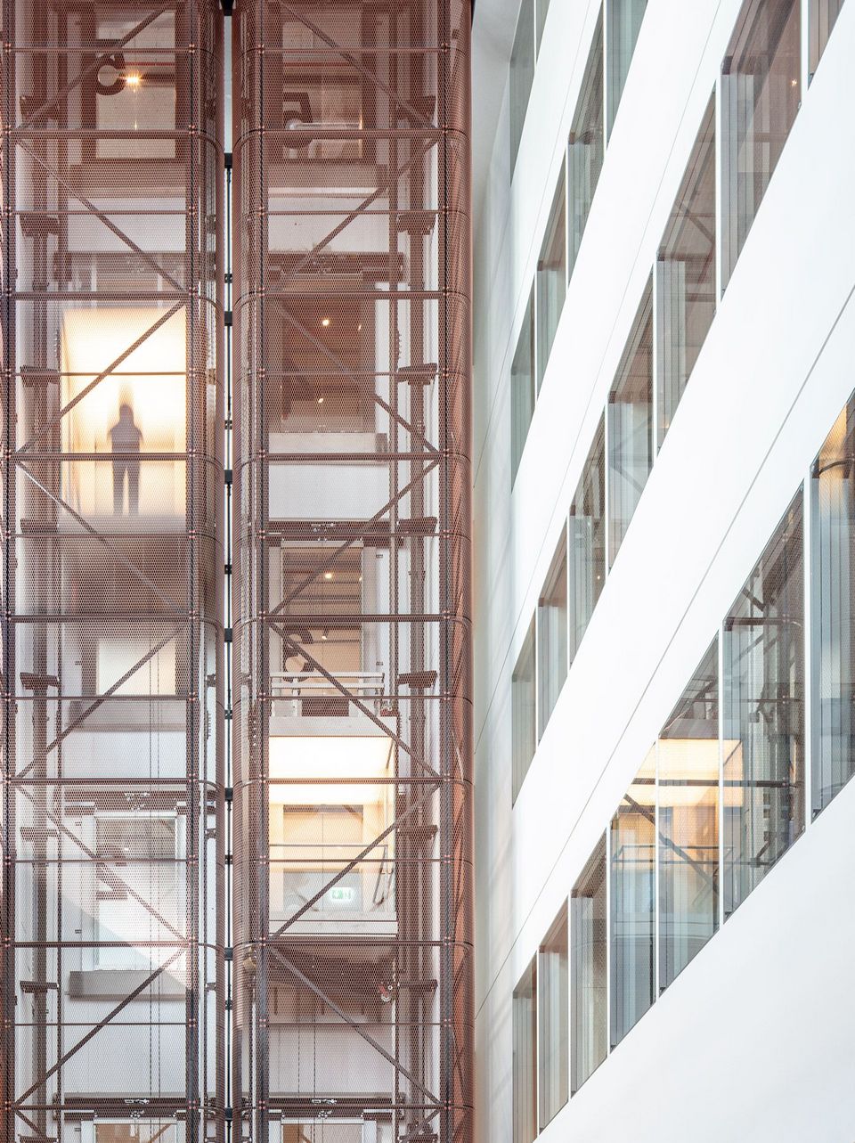 Innenansicht eines Atriums mit filigraner Metallstruktur und Glasflächen, Blick auf mehrere Ebenen mit offenen Arbeitsbereichen