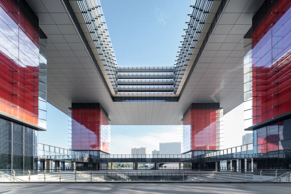 Außenaufnahme eines Gebäudekomplexes mit zwei auskragenden Baukörpern, verglasten Verbindungsstegen und markanter Öffnung im Zentrum.