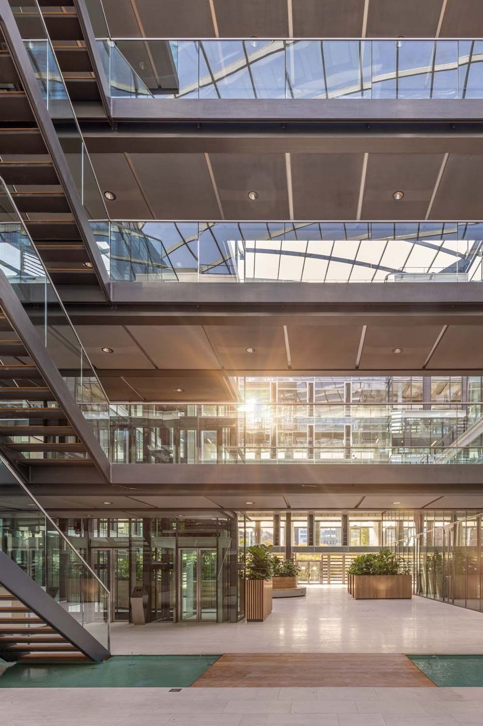 Mehrgeschossige Bürostruktur mit Glasfassaden und offenen Galerien, Atrium mit Tageslicht und Pflanzeninseln