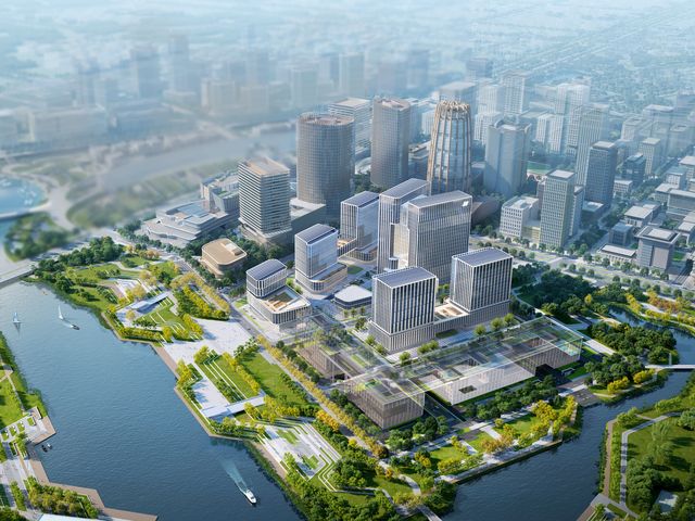 Luftaufnahme eines weitläufigen Stadtquartiers mit modernen Büro‑ und Mixed‑Use‑Gebäuden, grünen Uferzonen und klar strukturierten Wegen entlang eines Flusslaufs.