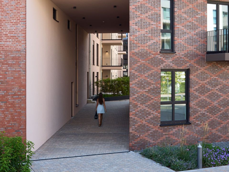 Außenaufnahme eines Wohngebäudes mit durchgesteckter Passage, Innenhofzugang und klar strukturierter Klinkerfassade.