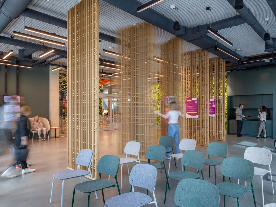 Interior with open seating areas and decorative wooden slats as room dividers, modern lighting and flexible furnishings
