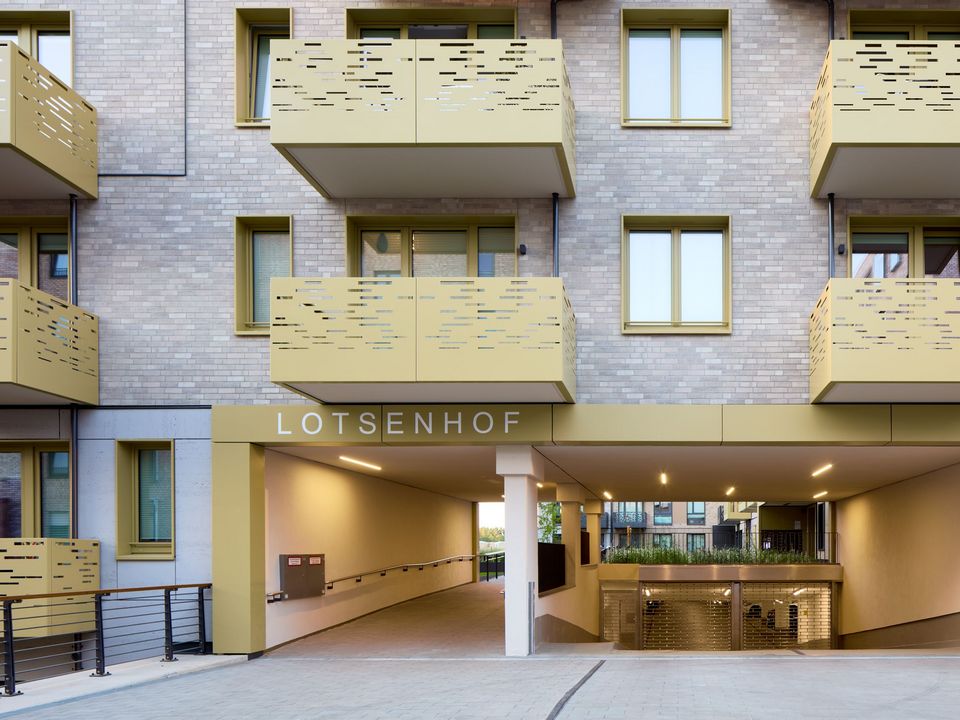 Außenaufnahme eines Wohngebäudes mit strukturierten Balkonen und überdachtem Durchgang zum Innenhof des Lotsenhofs.