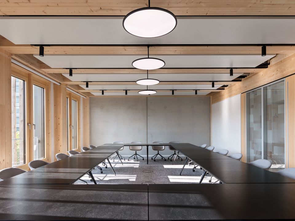 Conference room with large U-shaped table, wood panelling and round pendant lights, bright and functional design