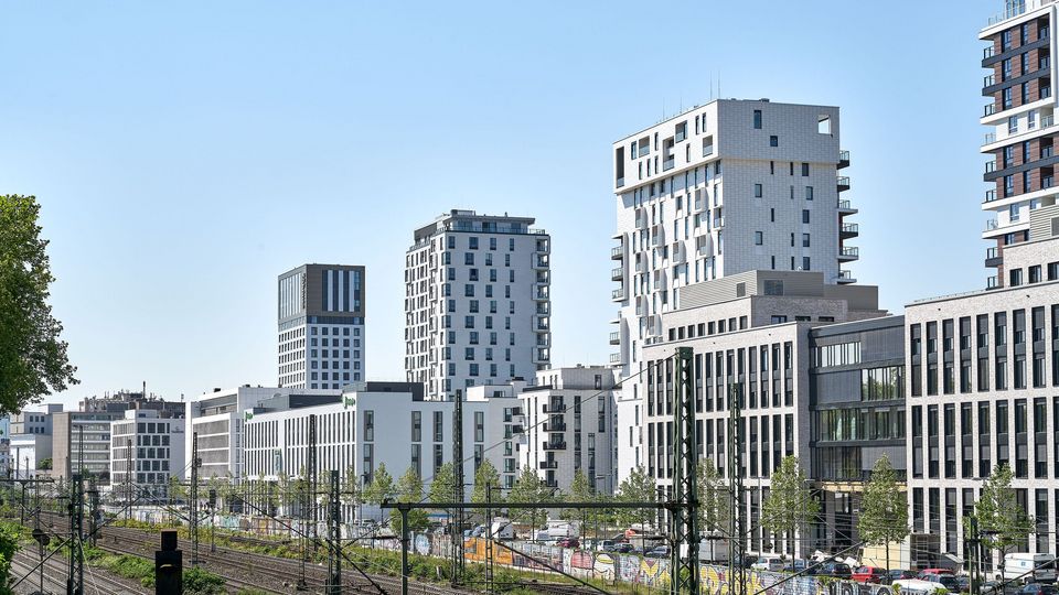 Städtisches Quartier mit mehreren Hochhäusern und modernen Wohngebäuden, klare Linien und helle Fassaden entlang einer Bahntrasse