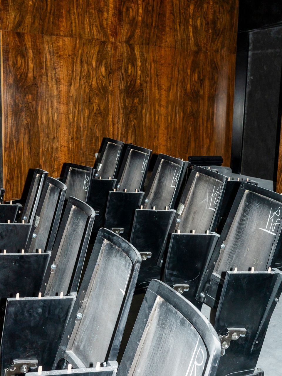 Reihe alter schwarzer Theaterstühle in einem historischen Innenraum