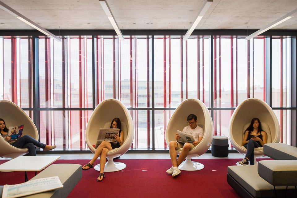Innenaufnahme eines Lounge‑ und Zeitungsbereichs mit geschlossenen Sitzschalen und großformatiger Fensterfront.