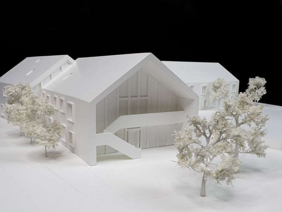 Modellperspektive eines Gebäudes mit offenem Giebelbereich und umlaufenden Modellbäumen, dargestellt in reduzierter weißer Architekturmodellsprache.