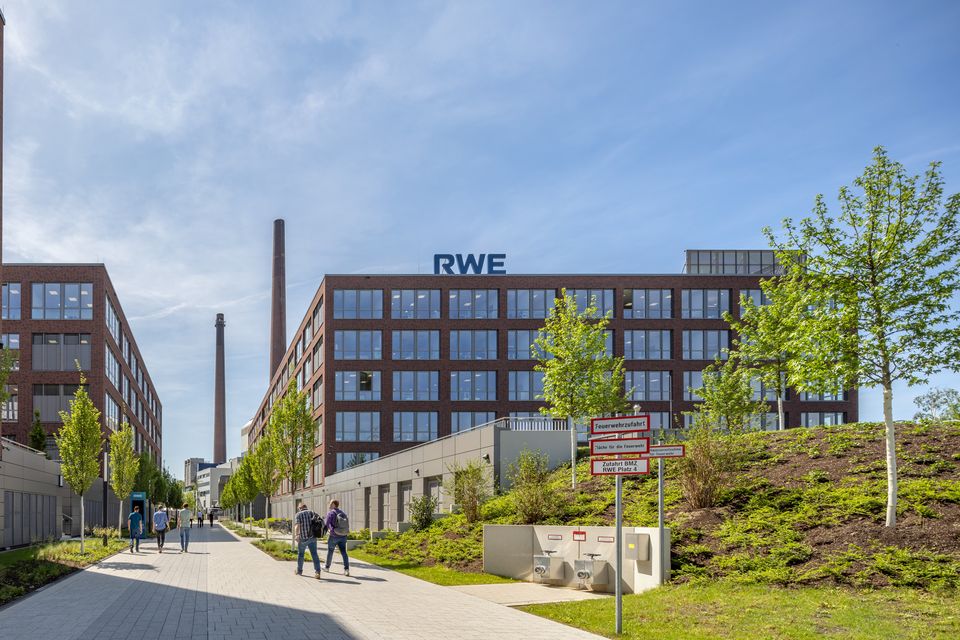 Außenaufnahme des RWE Campus mit klar gegliederter Ziegelfassade, flankierenden Wegen und begrünten Freiräumen im städtischen Kontext.