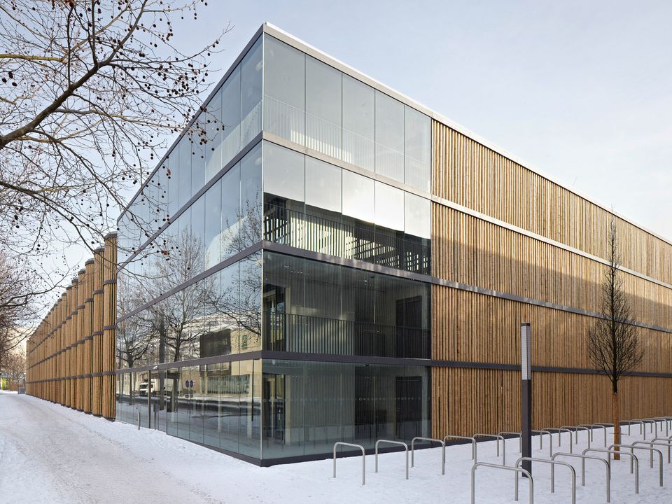 Modernes Parkhaus mit Glasfassade und vertikaler Holzverkleidung, klare Linien und transparente Architektur im winterlichen Umfeld