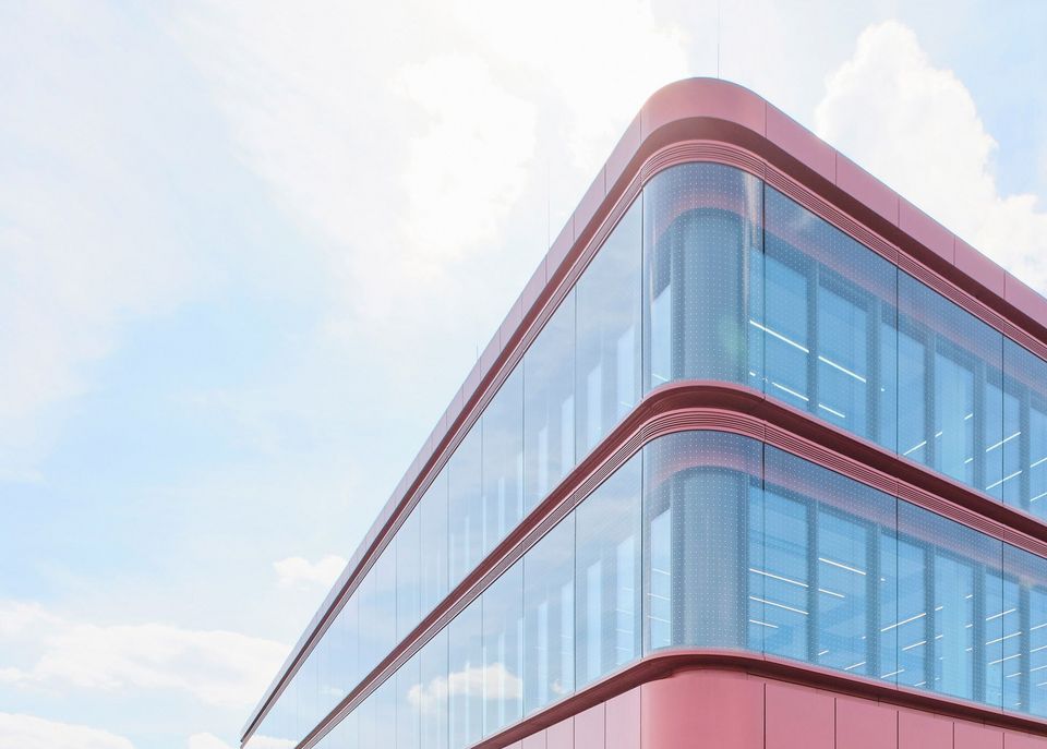 Detail view of a curved glass façade with multi-storey window bands and a dynamic façade profile under a bright sky.