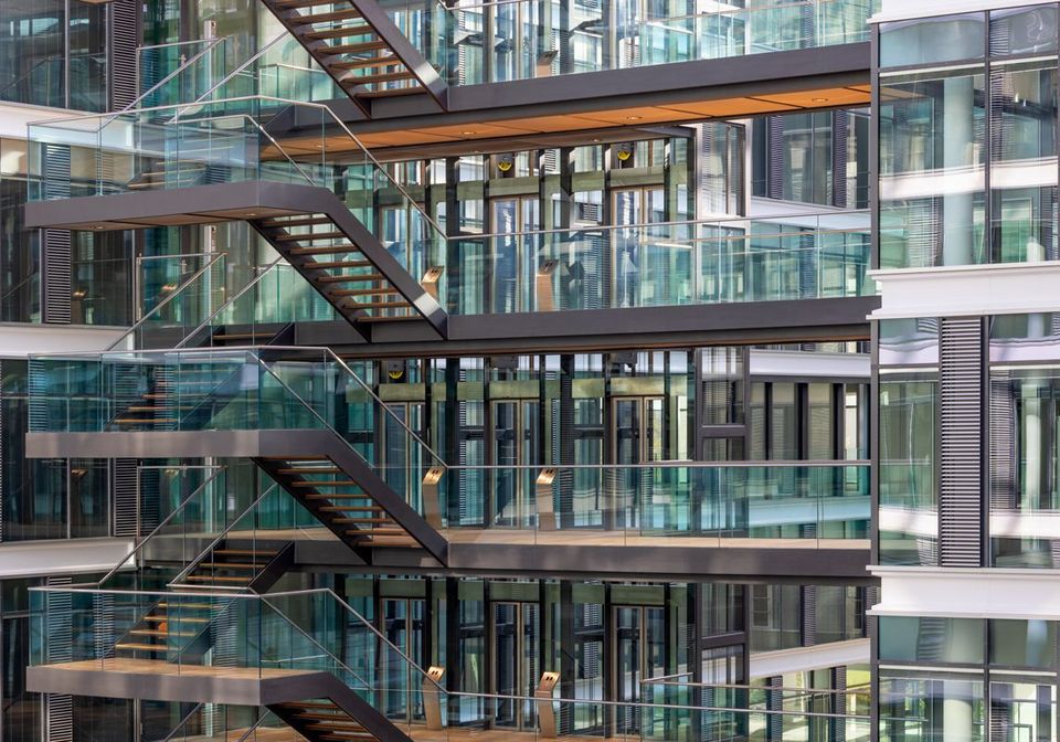 Open staircase with glass railings in a multi-storey office building, transparent architecture and clean lines