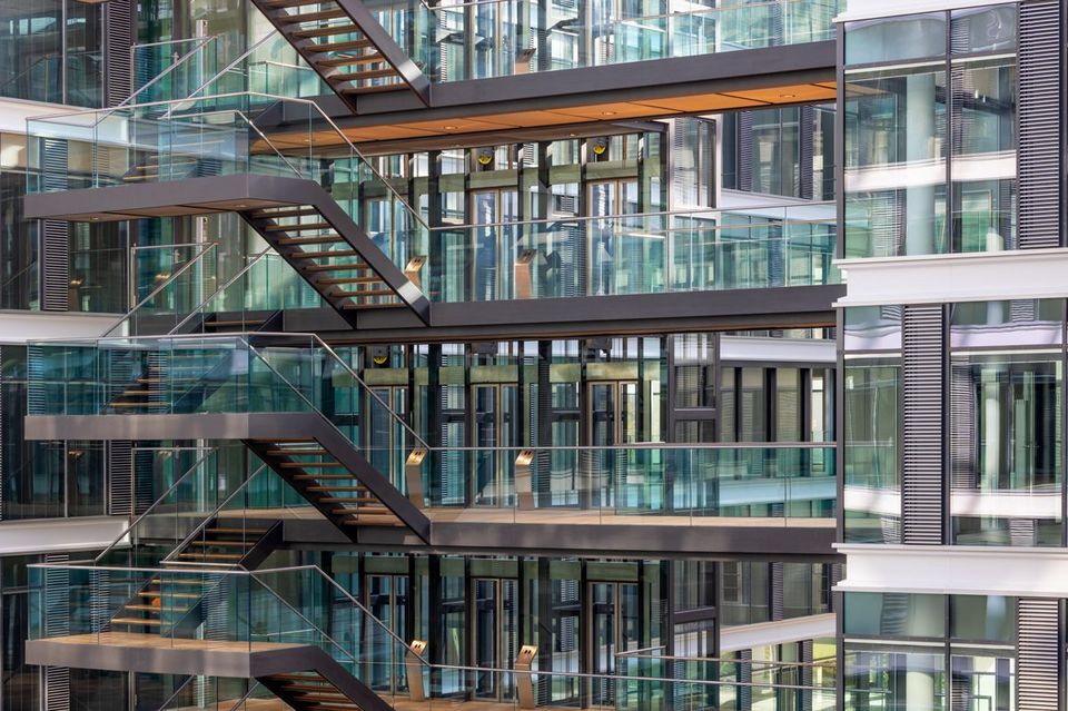 Offene Treppenanlage mit Glasgeländern in mehrgeschossigem Bürogebäude, transparente Architektur und klare Linien