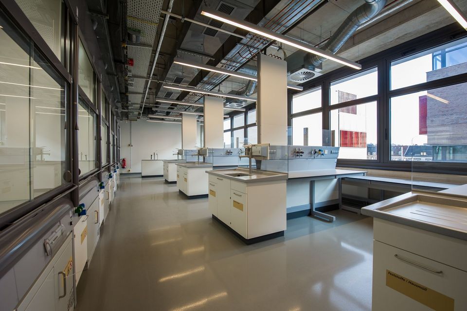 Innenaufnahme eines Laborraums mit modularen Arbeitstischen, technischen Installationseinheiten und durchgehender Fensterfront.