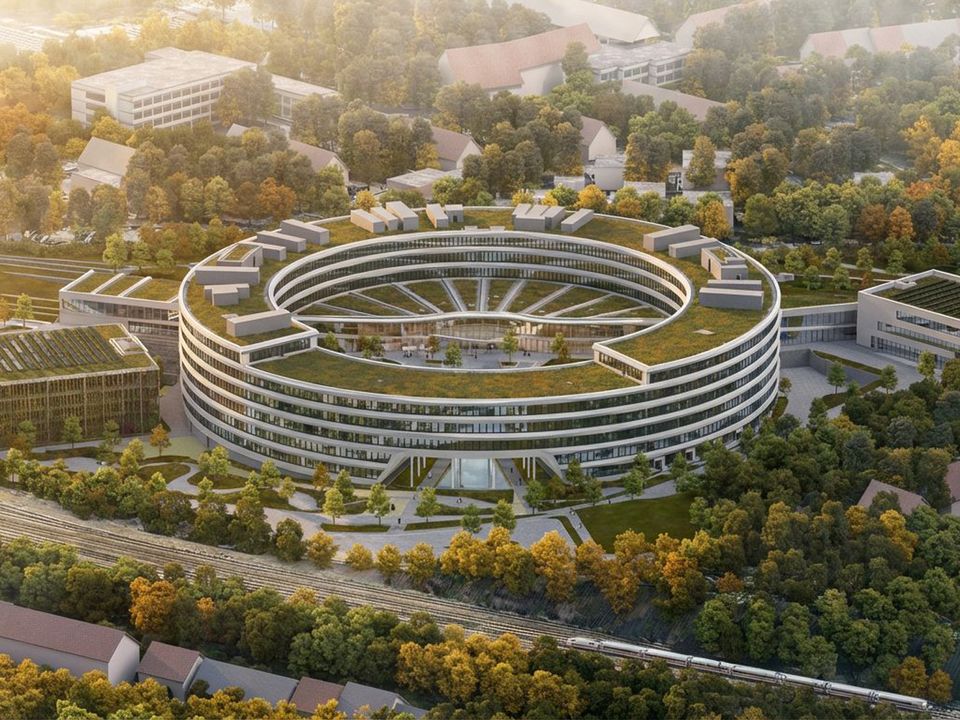 Luftvisualisierung eines ringförmigen Büro- und Forschungsgebäudes mit begrünten Dachflächen, terrassierten Ebenen und umliegender Parklandschaft.
