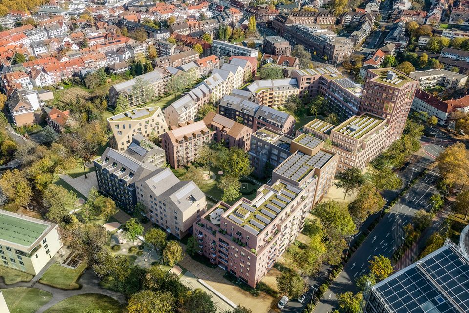 Luftvisualisierung eines Wohnquartiers mit blockartiger Struktur, begrünten Innenhöfen und umlaufenden Wegen im städtischen Kontext.