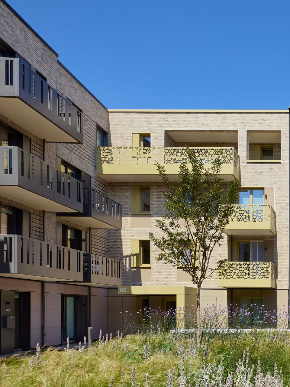 Exterior view of a planted courtyard with balconies and surrounding residential buildings.