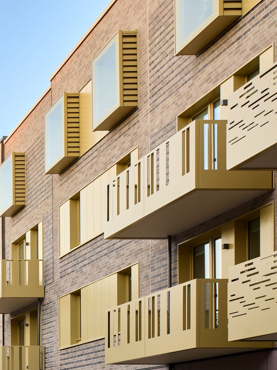 Außenaufnahme der Fassadenstruktur mit profilierten Balkonen und versetzten Fensteröffnungen eines Wohngebäudes.