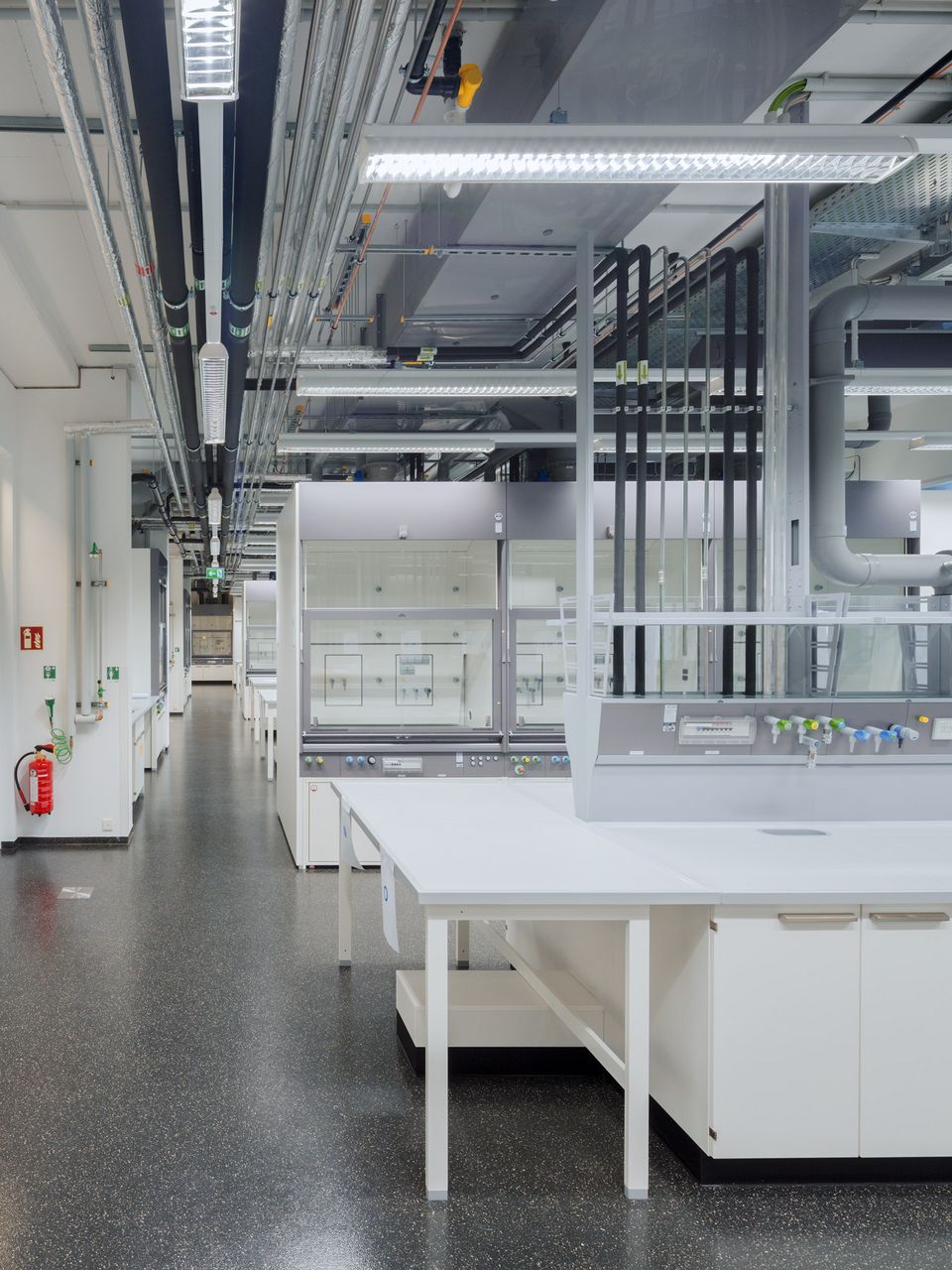 Innenaufnahme eines naturwissenschaftlichen Laborraums mit modularen Arbeitsplätzen und umfangreicher technischer Infrastruktur.